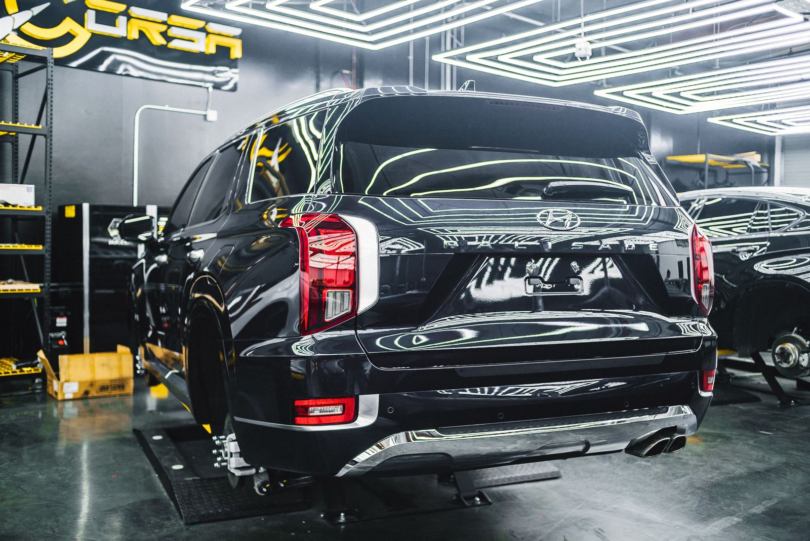 An SUV raised on a hydraulic lift in a bright modern detailing garage