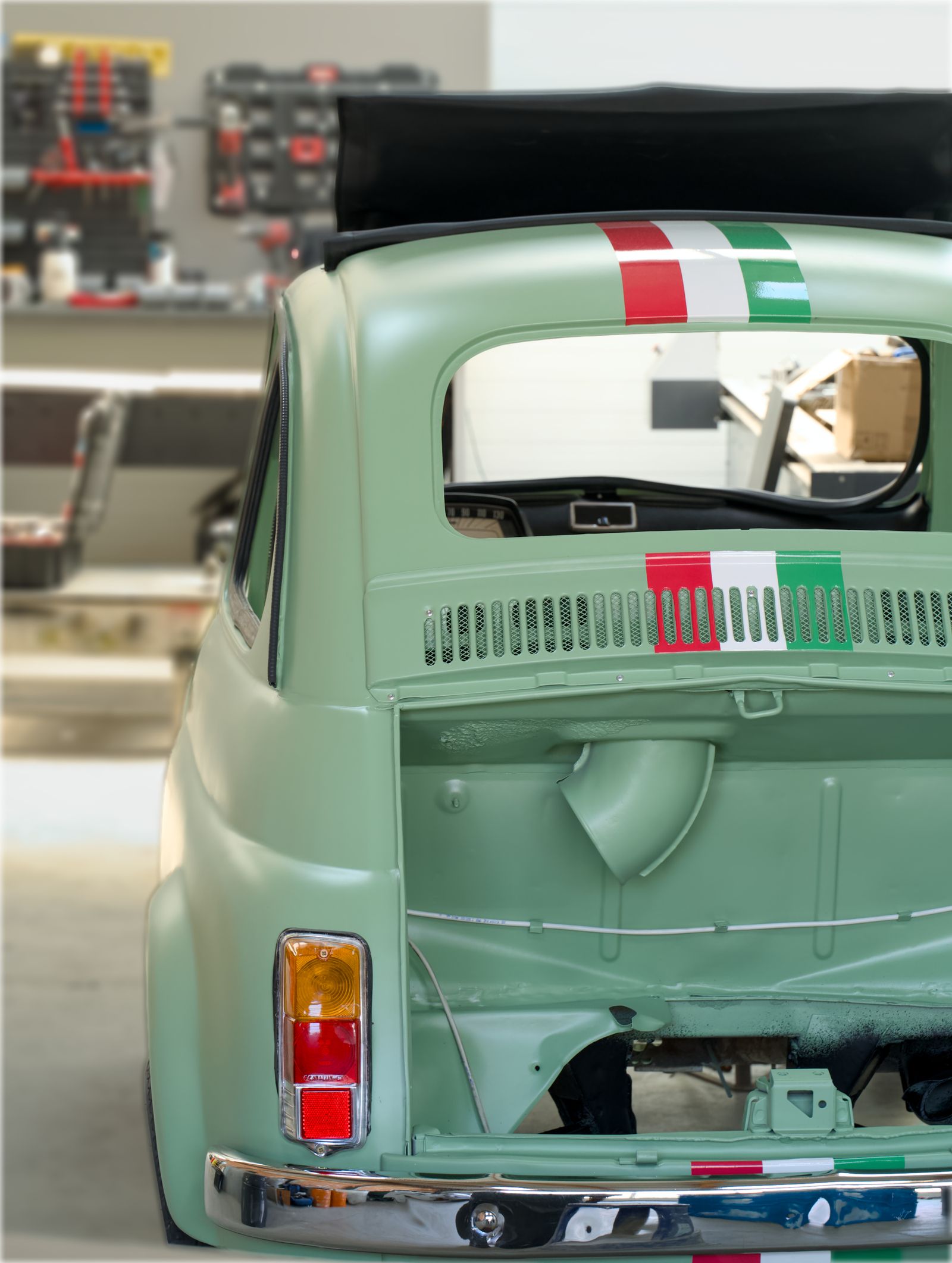A vintage car undergoing paint restoration inside a detailing workshop