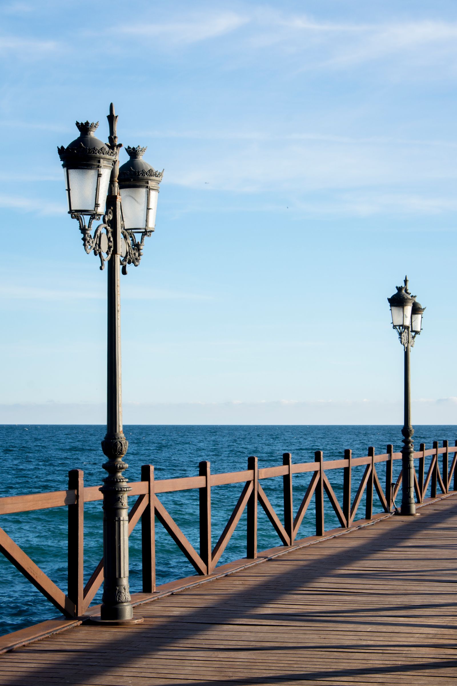 Wooden pier with vintage lamps overlooking the Mediterranean Sea