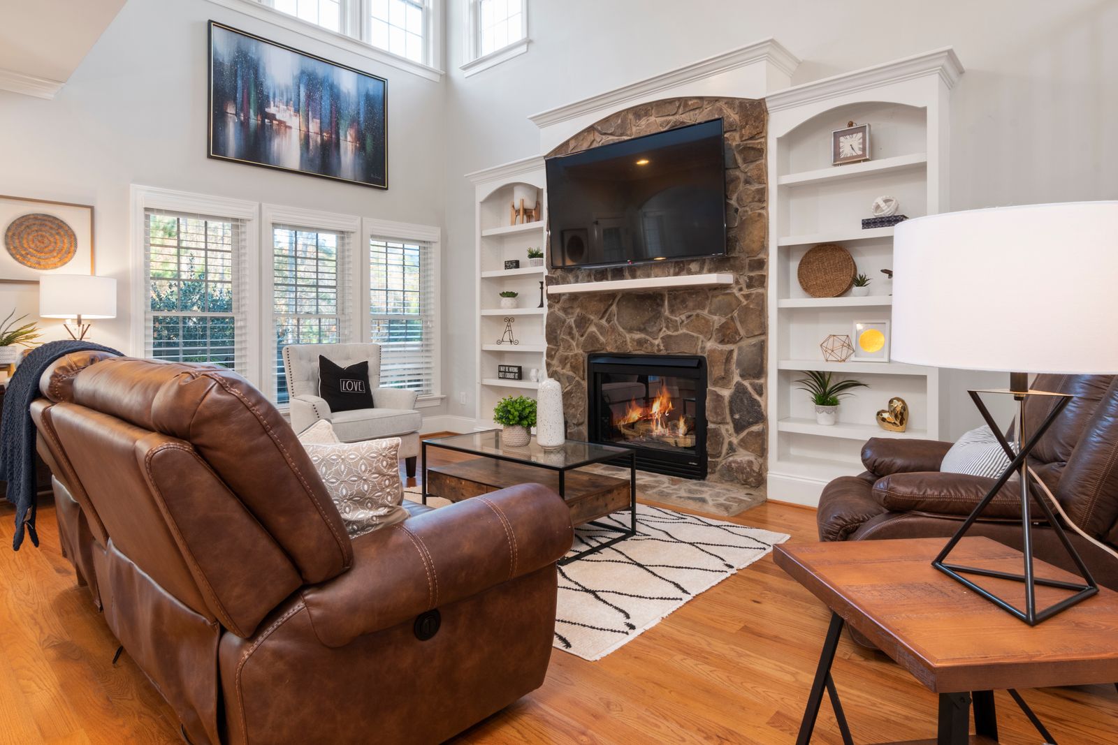 Cozy living room with a stone fireplace, leather sofas, and warm decor