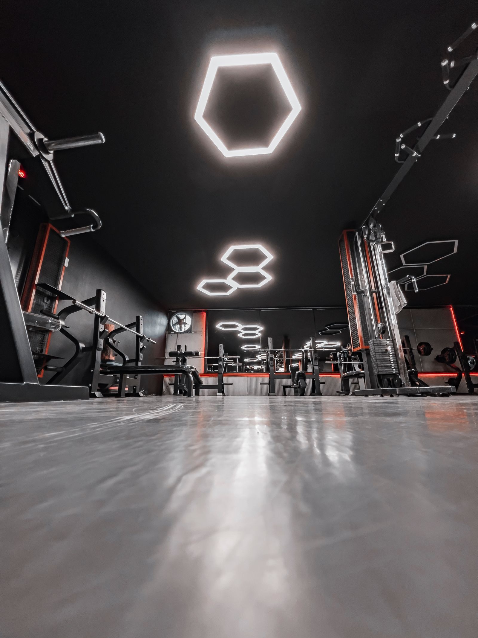 Modern gym interior with geometric ceiling lighting over the equipment floor