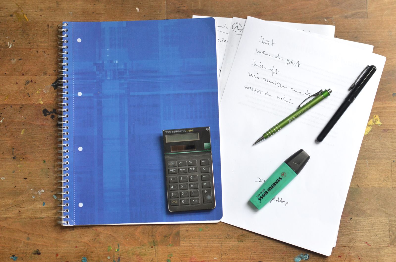 A notebook and office supplies arranged on a wooden desk