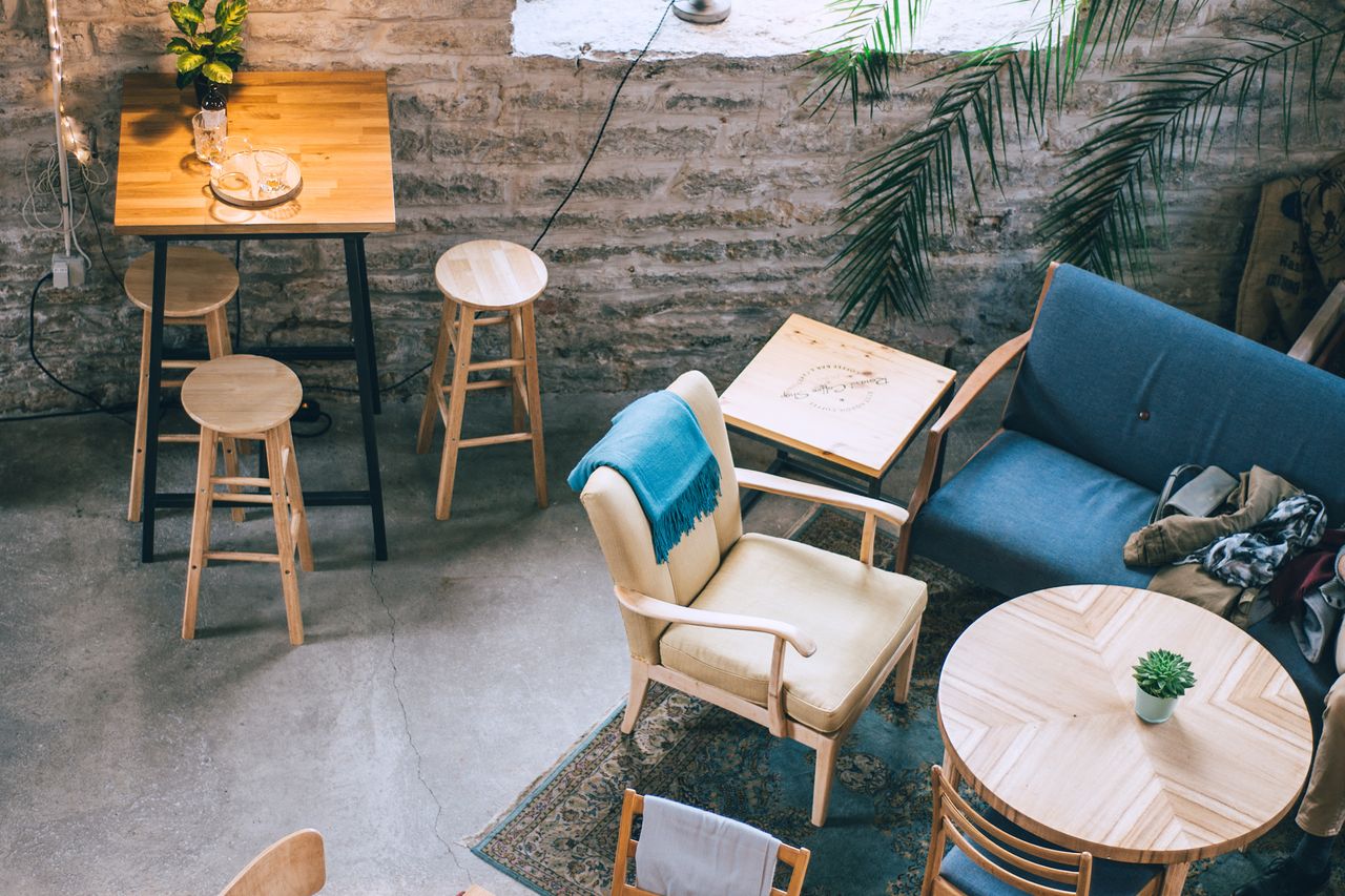 The Grindstone café: rustic stone walls, wooden furniture, and plants by a tall window