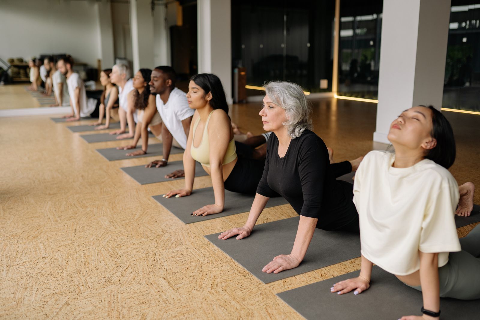 A group of adults practicing yoga together in a bright, calm studio