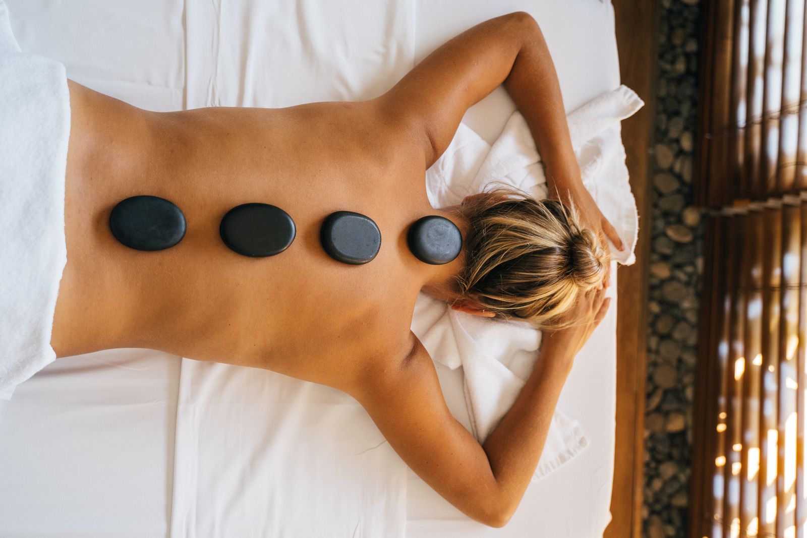 Smooth hot stones placed in a row on a person's back during a massage