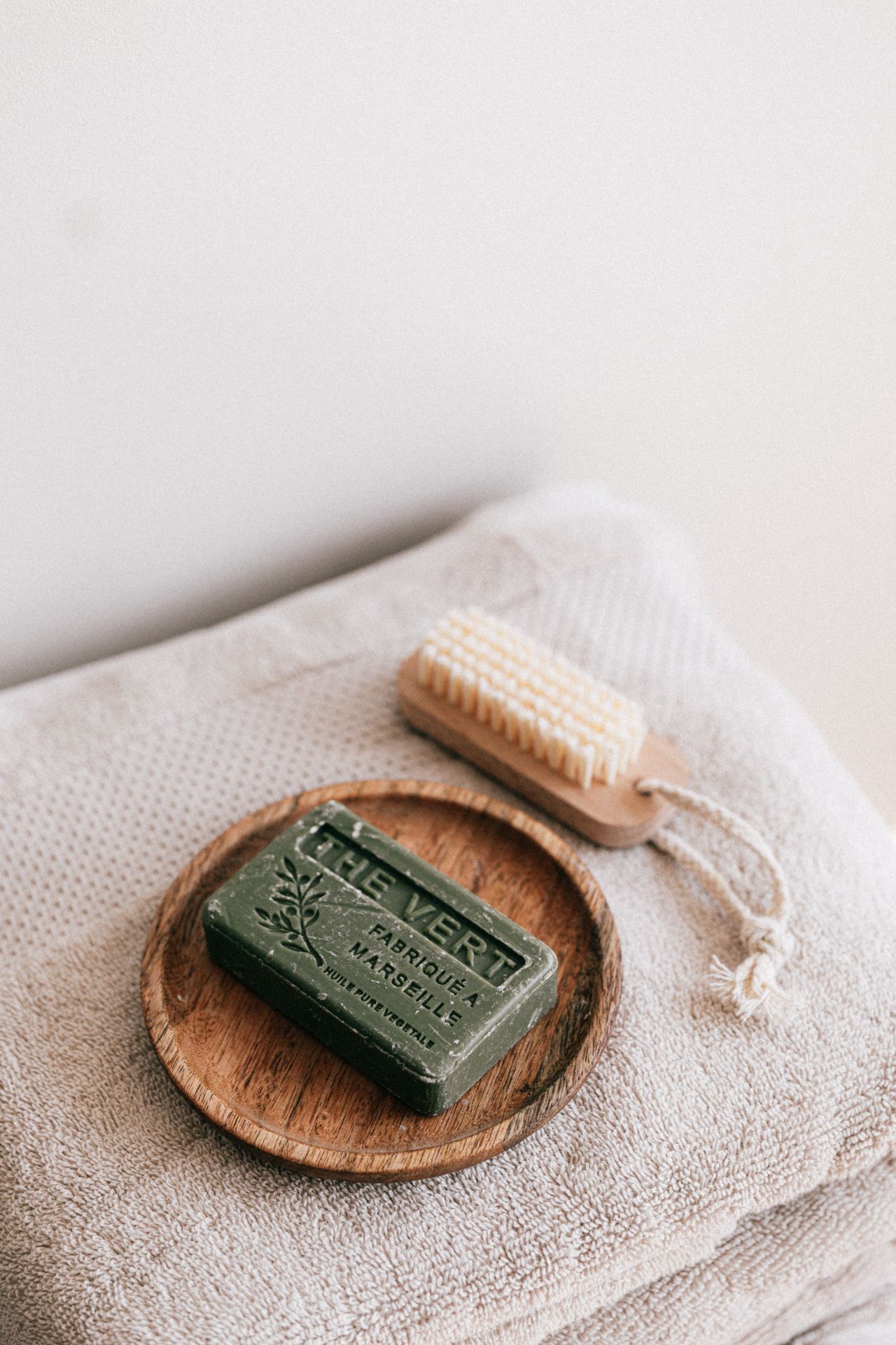 A neat stack of natural soap, a wooden brush, and folded towels