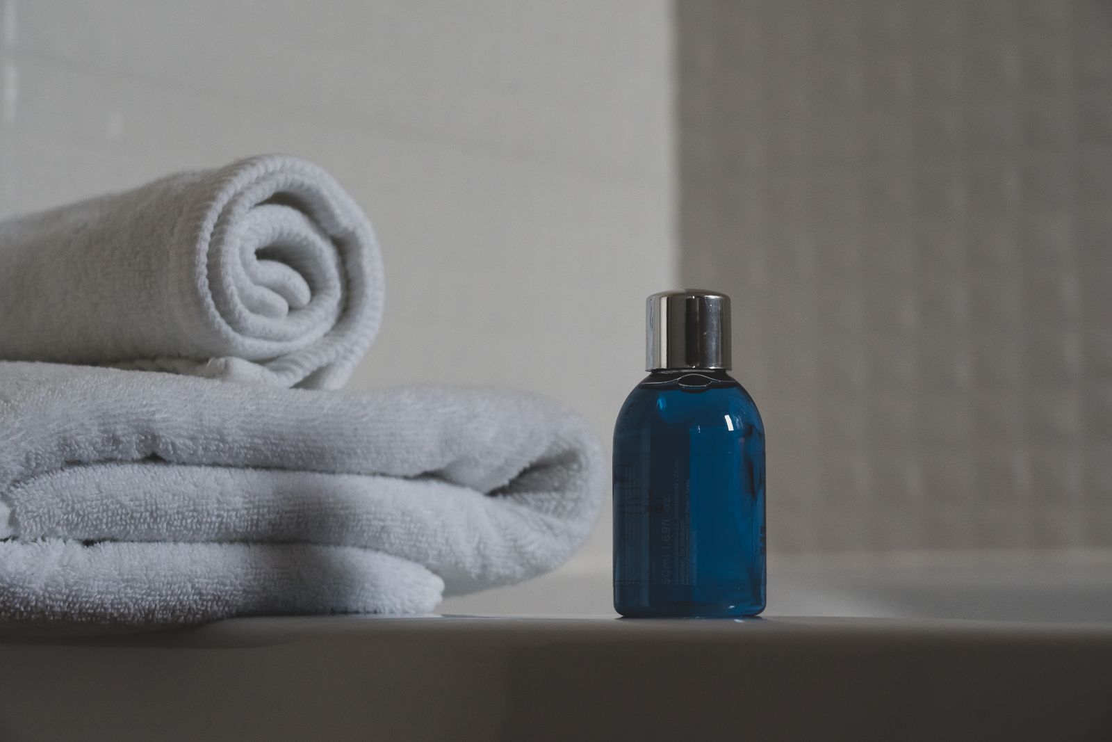 A glass spa-oil bottle resting beside a rolled white towel