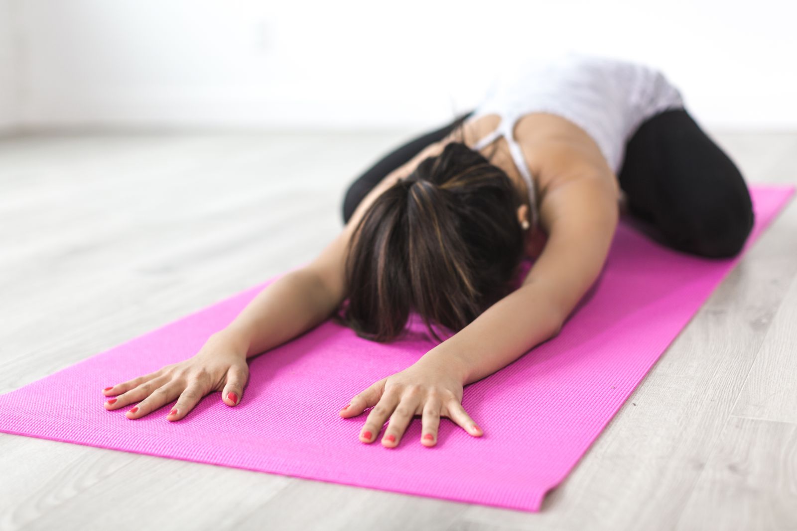 A woman holding a grounded, balanced yoga pose on a warm-toned mat