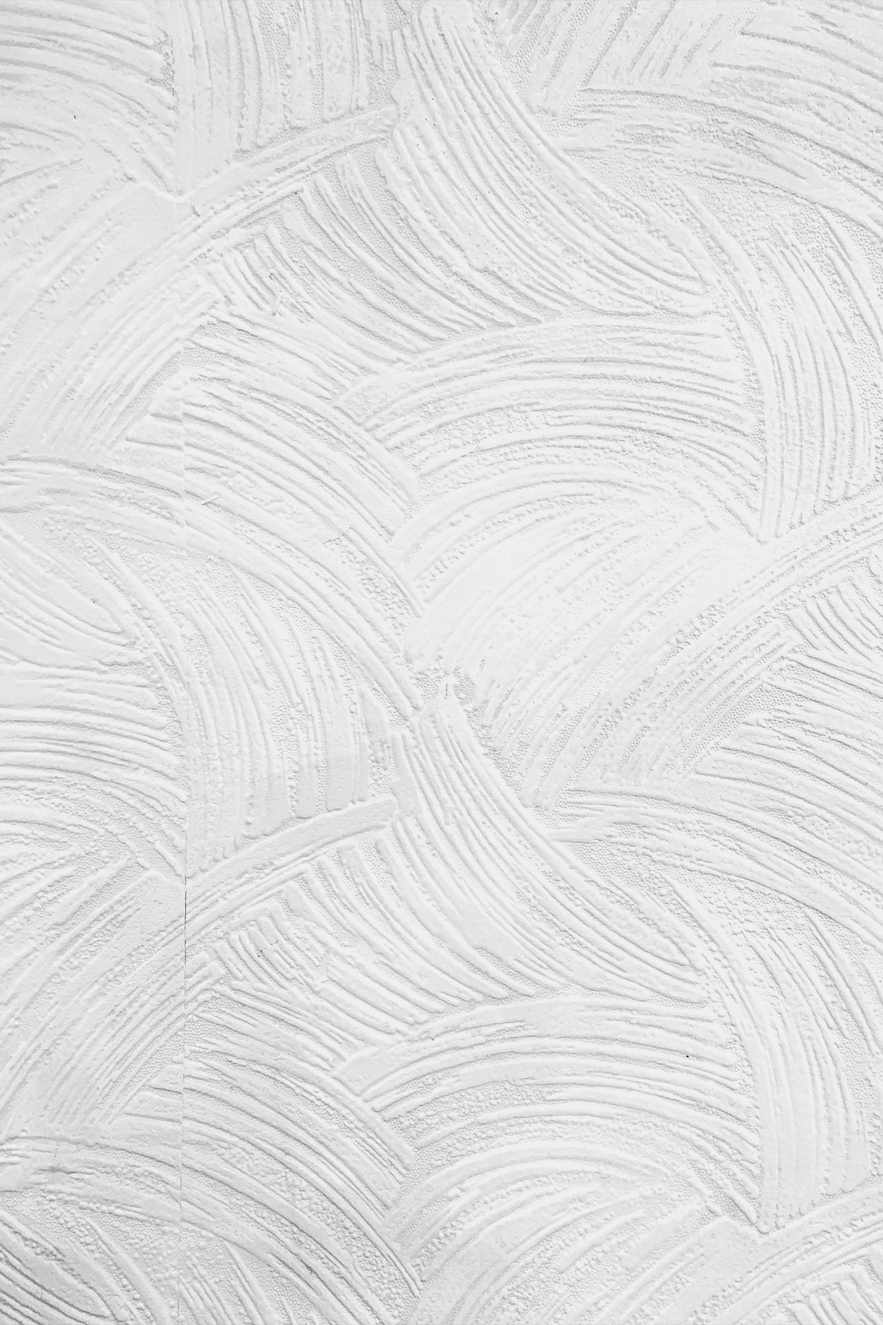 Close-up of a white plaster wall with swirling decorative trowel marks