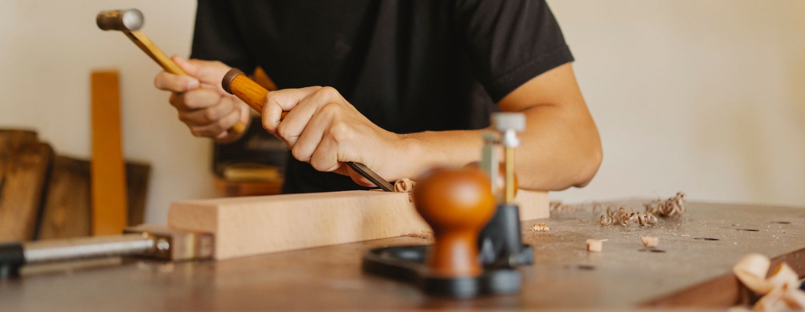 Craftsman using hand tools to shape a piece of wood in a workshop