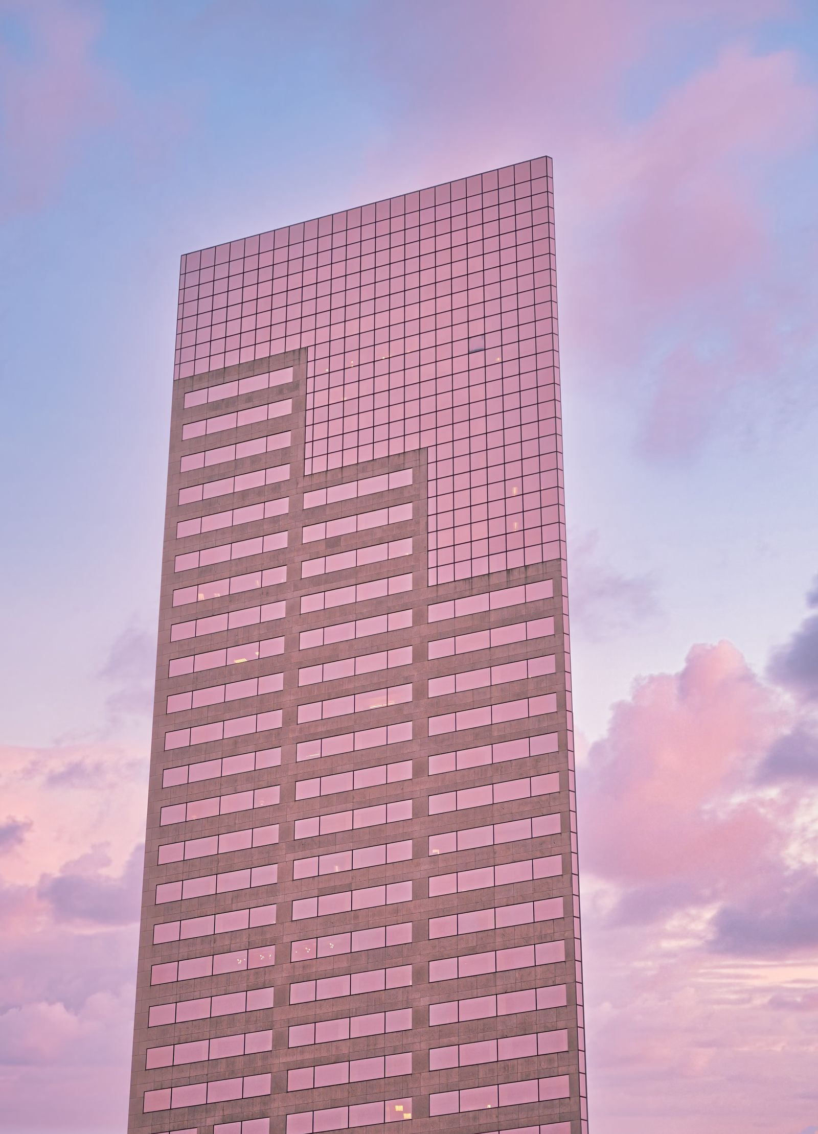Contemporary skyscraper with mirrored glass facade reflecting a colorful sunset sky