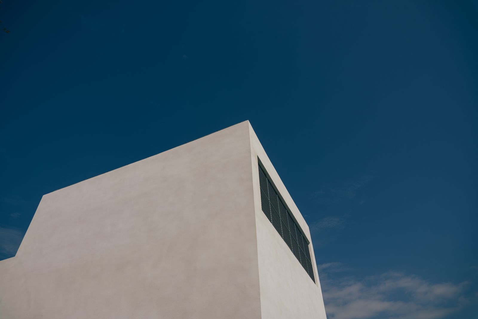 Sharp angular minimalist building facade set against a clear blue sky